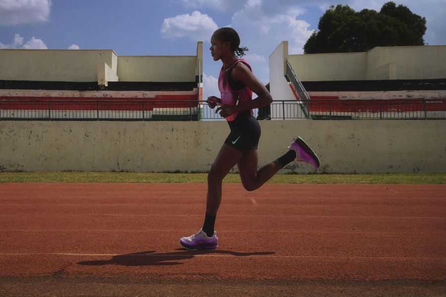 Faith Kipyegon running on a track, in a pink and black outfit