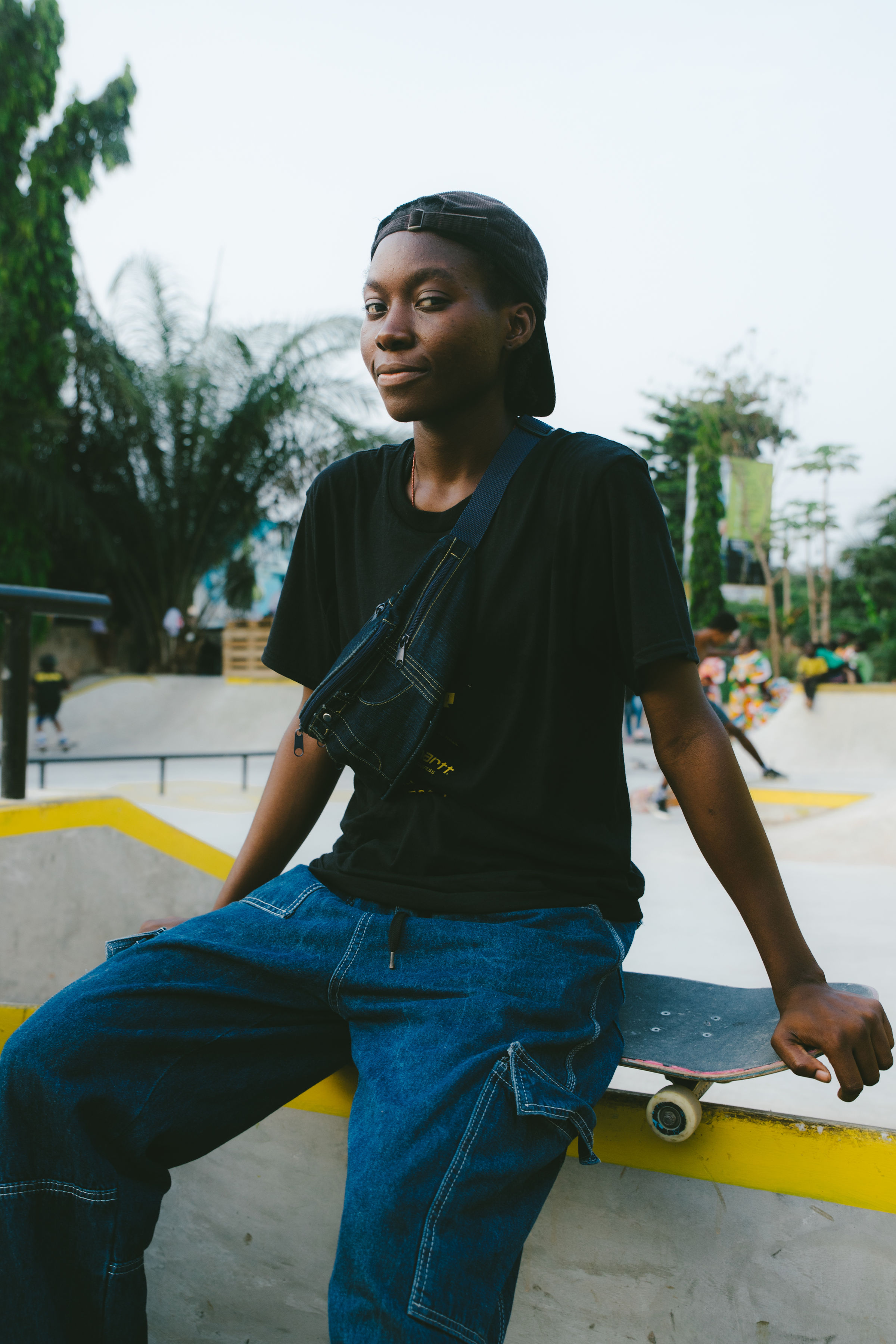 Harmonie Bataka sitting on a skatepark obstacle, a board beside her