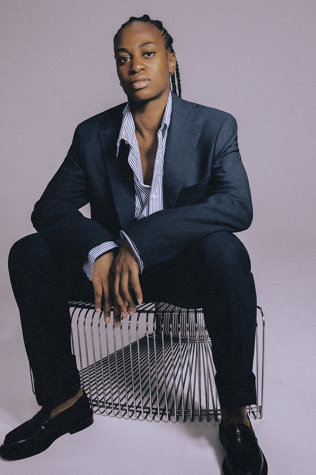Marie-Antoinette Katoto seated in a navy blue suit and striped shirt, studio photograph for SNA
