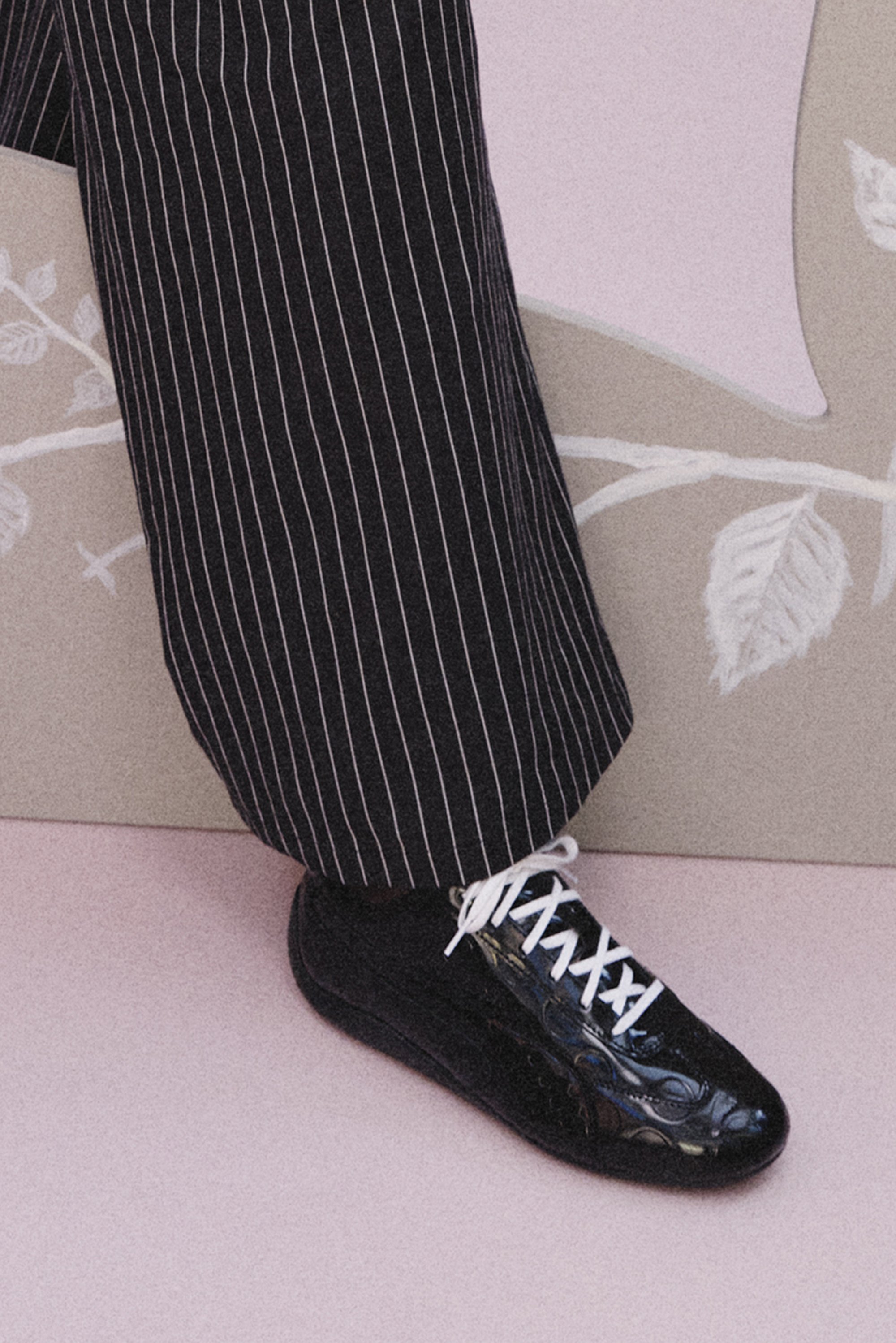 A black patent shoe worn with pinstripe trousers