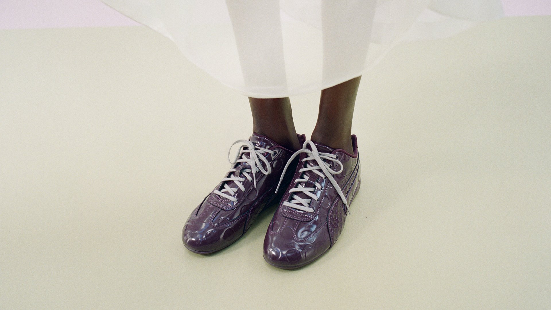 Purple patent shoes worn under a white garment
