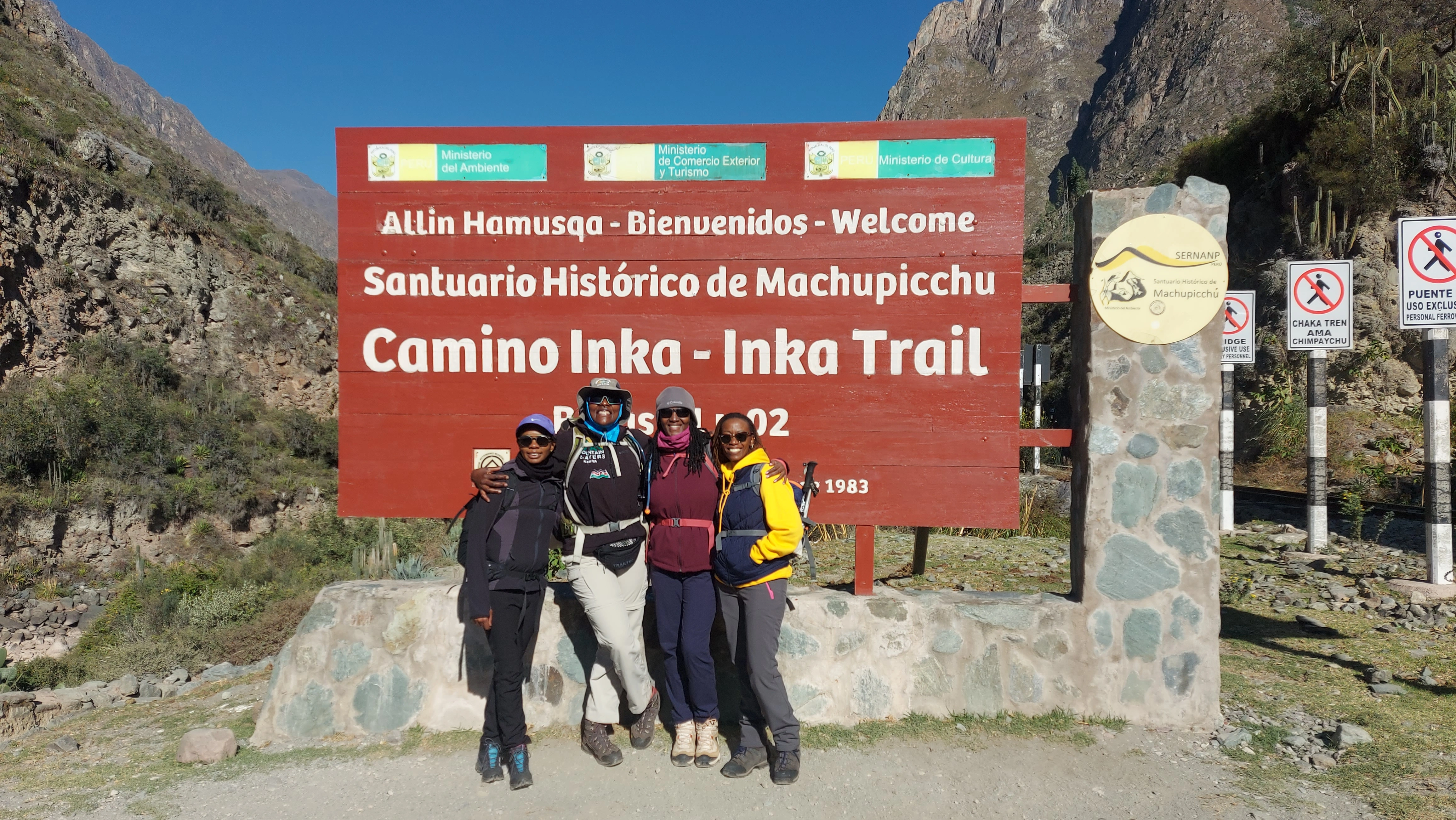 A group of hikers in front of the Inca Trail sign at Machu Picchu
